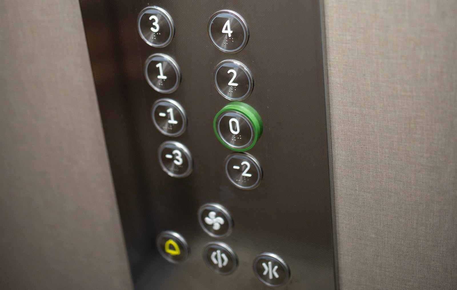 A modern elevator control panel with illuminated floor buttons
